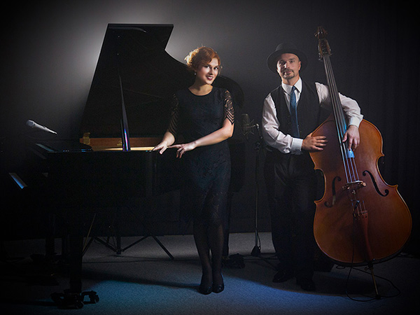Solo-Pianistin Yuliya Drogalova steht vor einem schwarzen Flügel, neben ihr steht der Kontrabassist Bartek Mlejnek
